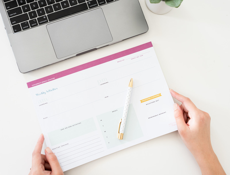a close up of a person looking at a planner and a laptop nearby